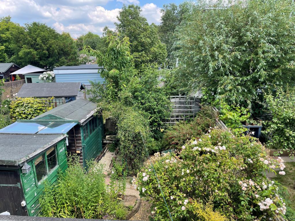 Lot: 19 - HOUSE IN NEED OF REFURBISHMENT AND REPAIR - View of rear gar from first floor with sheds and flower borders